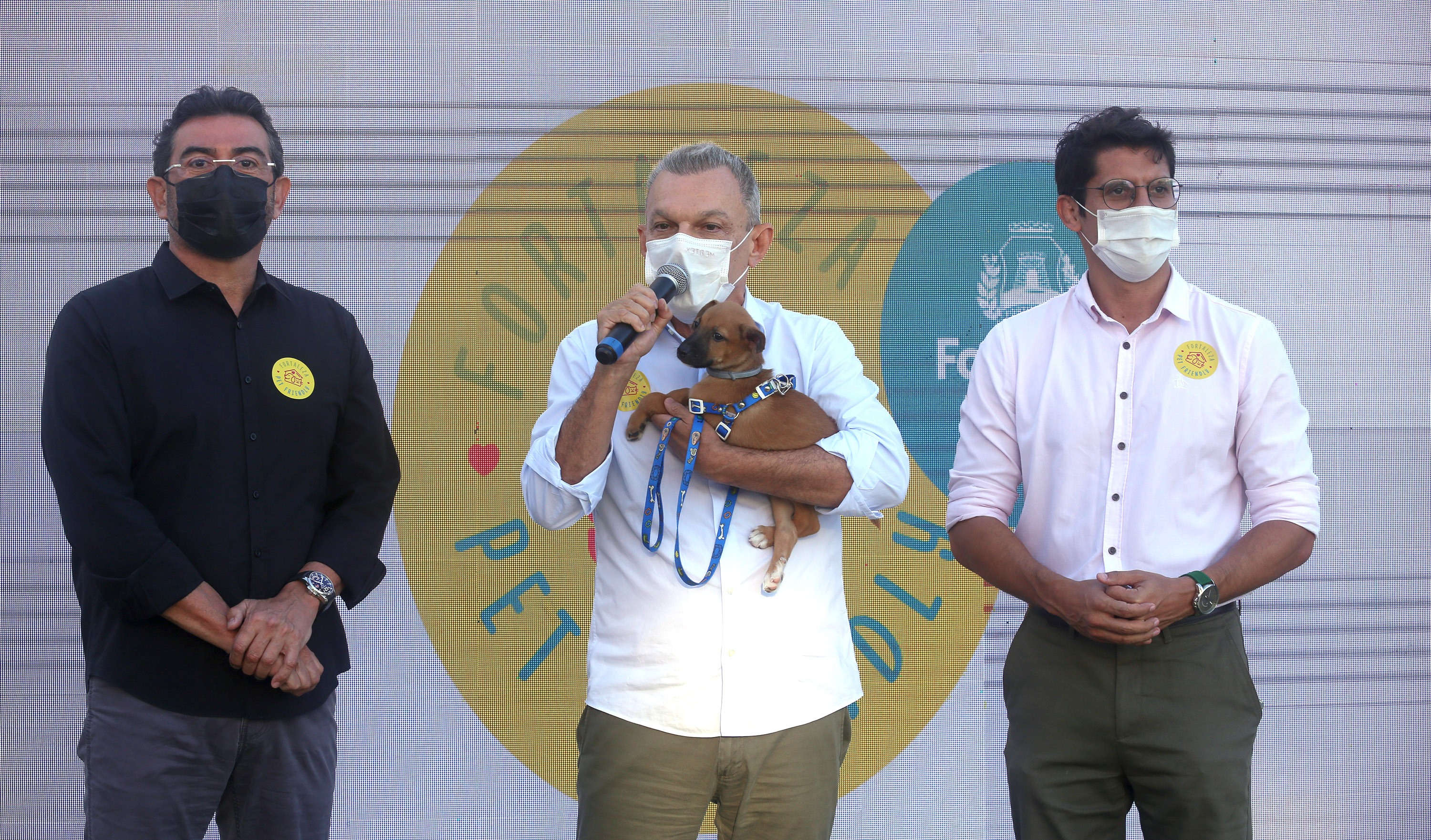 prefeito com seu cachorro de estimação no colo enquanto fala ao microfone